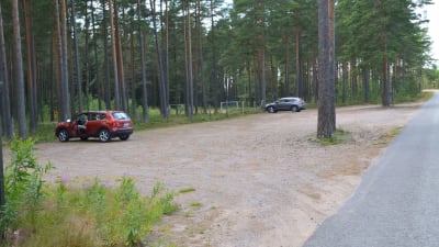 Parkeringsplats av sand med ett par bilar.