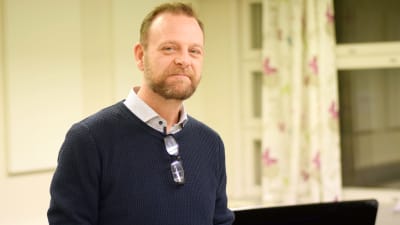 En man med lite skägg i en skolsal