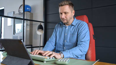 Roni Collin sitter vid sitt skrivbord och knäpper med fingrarna på tagentbordet.