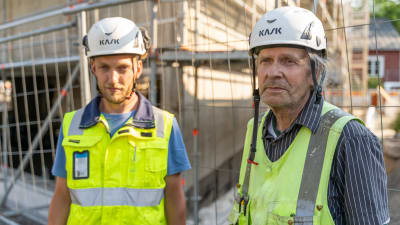 Två män står vid en byggarbetsplats. 