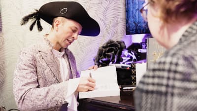 Victor Dixen signeeraa kirjan.