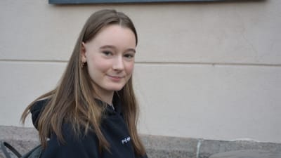 Wilma Rönnlund, en tjej i tonåren, med långt brunt hår, ler mot kameran.