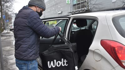 Woltmatbud lägger in en woltkasse i en bil.