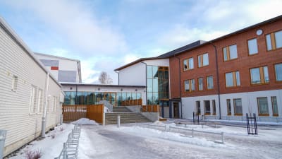 Skolbyggnader i vitt och brunt med stora fönster.