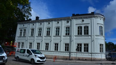 vitt gammalt stenhus i två våningar invid Domkyrkan och Åbo akademis huvudbibliotek. Vi paketbil i förgrunden