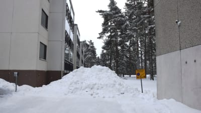 Bild på en snöhög på en parkeringsplats, brevid snöhögen finns ett märke som visar räddningsväg.