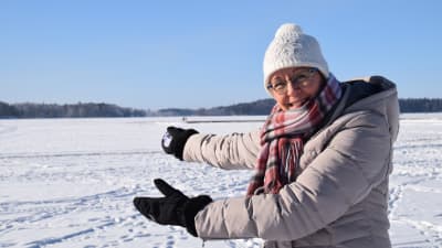 En kvinna står vid en snöklädd och isklädd sjö.