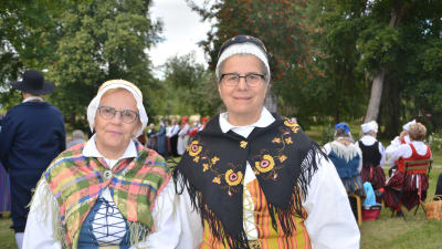 Två kvinnor i en park iklädda folkdräkter.