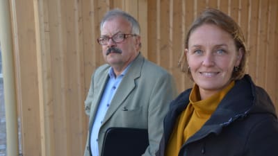 Man och kvinna poserar vid brädfasad