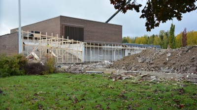 nya träbalkar vid ett tegelhus och bredvid en stor hög med sten och grus