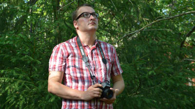 Niclas Rantala står i skogen med kamera i handen.