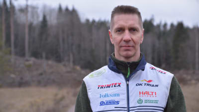 Man med orienteringsväst står på en åker och ser målmedveten ut.
