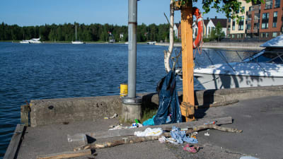 Skräp ligger ner på marken vid kajen, nära vattnet.