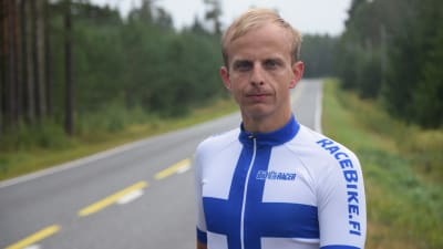 En man står vid en landsväg och tittar in i kameran. Han har en tajt trikåtröja i blått och vitt på sig. Han heter Johan Nordlund.