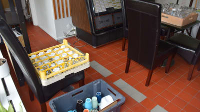 Glas, muggar och andra kärl i stora plastlådor på ett golv.