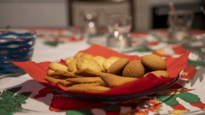 ett brödfat med tre olika sorters småbröd, kex. Bordet har en julduk med jultomtar och granar.