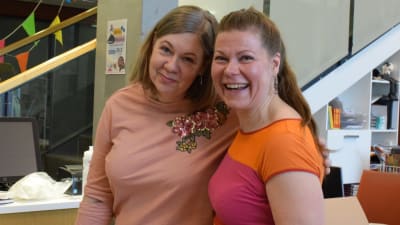 Tuovi Söderlund och Sari Hyvärinen står med armarna runt varandras axlar i Villa Landes café och ser glada ut.