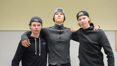 pojkarna håller om varandra i axlarna och tittar in mot kameran