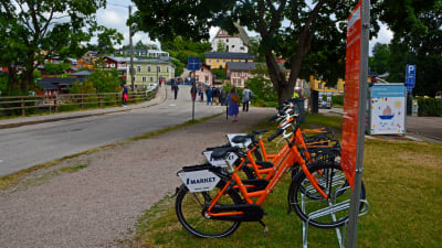 Orangefärgade cyklar står i en cykelställning.