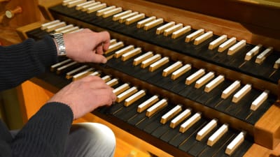 Närbild av händer som spelar på en kyrkorgel.