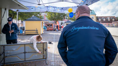 Sverigedemokraternas valarbetare står vid en valstuga.