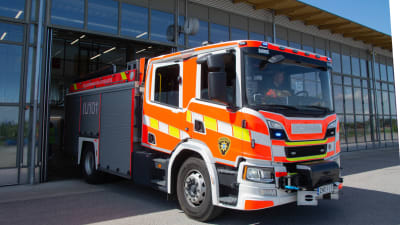 Brandbil som kör ut från räddningsverkets hall. 