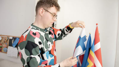 En man tittar på nordiska flaggor som står på ett bord.