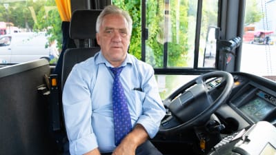 En man som sitter vid bussratten.