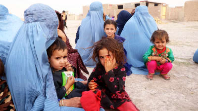 Afghanska flyktingar sitter på marken.