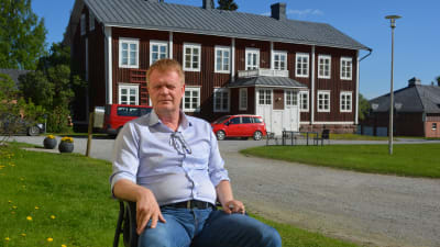 Carl-Johan Strömberg, direktör för Lagmansgården, sitter på en stol under strålande solsken.