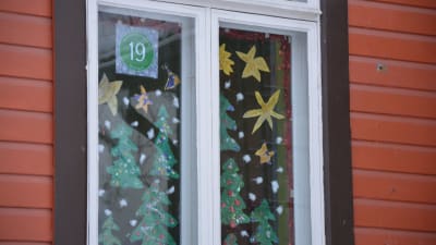 Flera julgranar i papper är fastklistrade i ett fönster. 