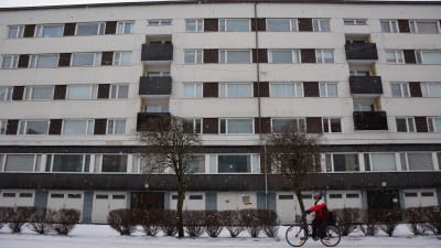 Person cyklar framför höghus en vinterdag i Vasa.