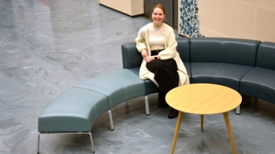 Vilma Kuvaja sitter på en soffa i Åbo universitets Medisiina-byggnad.