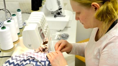 Linda Andersson syr haklappar på maskin.