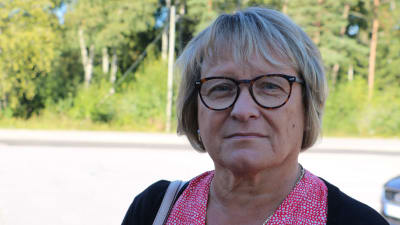 En kvinna med kort blont hår och glasögon ser bekymrad ut.