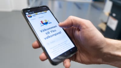 Närbild på mobiltelefon som visar upp startsidan för Svenska Yles valkompass med texten "Välkommen till Yles valkompass"