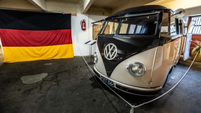 En gammal VW-minibuss, på väggen hänger en tysk flagga
