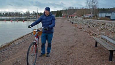En medelålders man leder en cykel längs med stranden vid Skeppsbron i Lovisa.