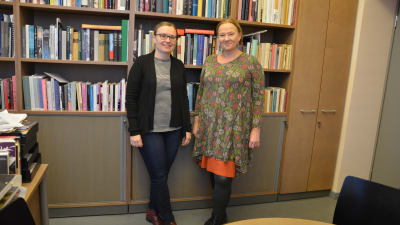 två kvinnnor står framför en bokhylla