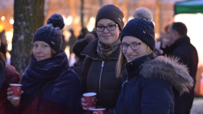 Tre unga kvinnor följer med ljusshowen då Åbo Akademi 100 år- jublieumsåret invigdes.