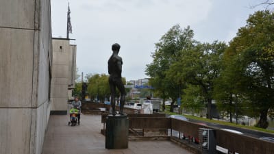 Wäinö Aaltonens museum utifrån, en staty av en man står i förgrunden, en kvinna skuffar en barnvagn i bakgrunden. 