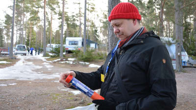 Kenneth Sandholm, en man med röd mössa, läser anvisningarna för hur man ska använda den nödraket han har i handen.