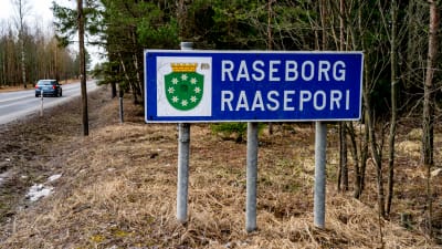 En skylt, där det står Raseborg, står i terrängen vid kommungränsen.