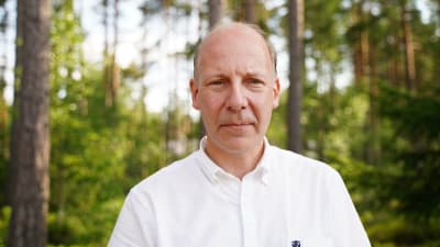 en man står vid ett skogsbryn,