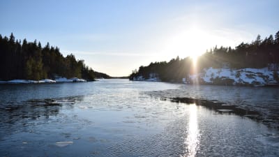 Vinterkväll i inre farleden i Barösund med solen som går ner över Bergvalla. Havet är öppet med enstaka simmande isflak.