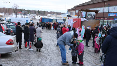 Två lastbilar står på torget i Kristinestad. Runt lastbilarna står abiturienter som firar sin penkisdag. Även intresserade Kristinestadsbor står samlade på torget.