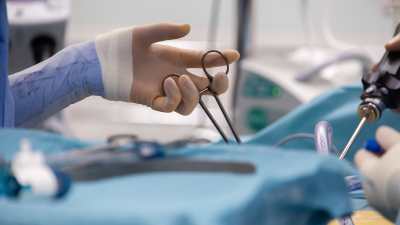 En hand som håller i ett kirurgiskt verktyg under en operation i en operationssal.