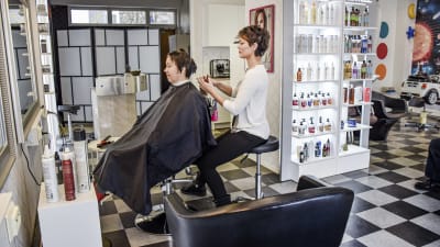 Vesna Gutic håller på att klippa håret på en kund i sin frisörsalong.