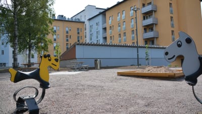 en gårdsplan med sandlåda och gungleksak för barnen