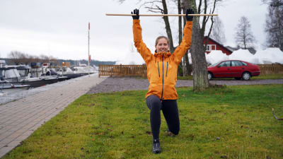 Hanna Kanerva visar pausgymnastik med ett kvastskaft.